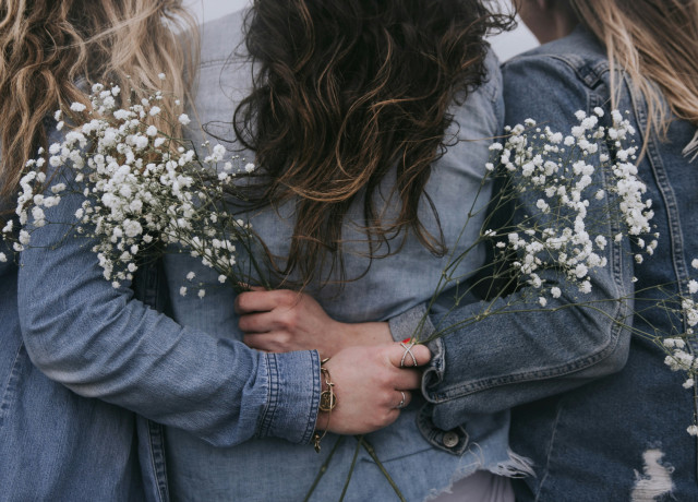 3 femmes de dos mains jointes avec fleurs blanches