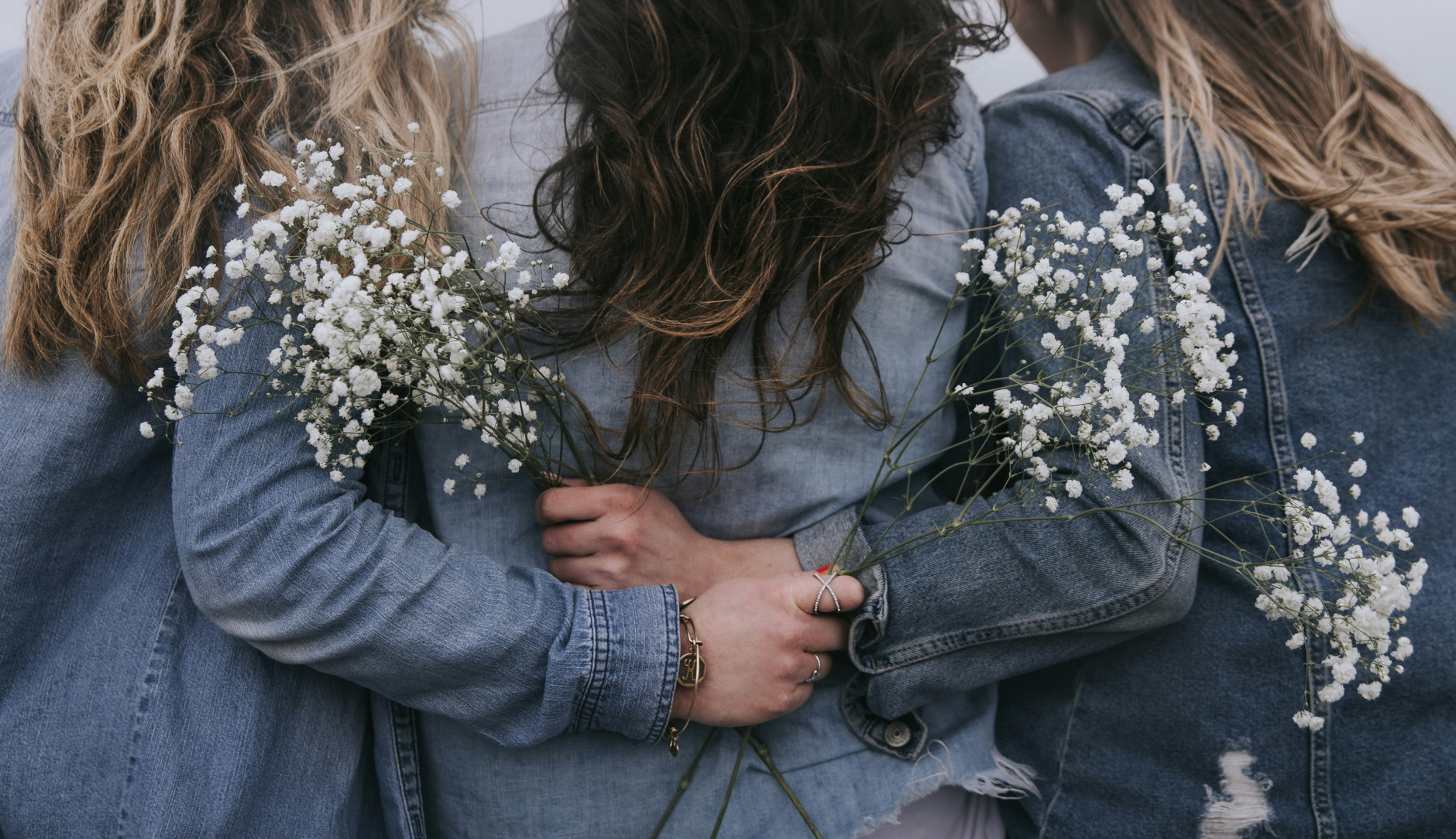 3 femmes de dos mains jointes avec fleurs blanches