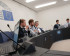 5 hommes assis derrière un bureau avec un intervenant au micro