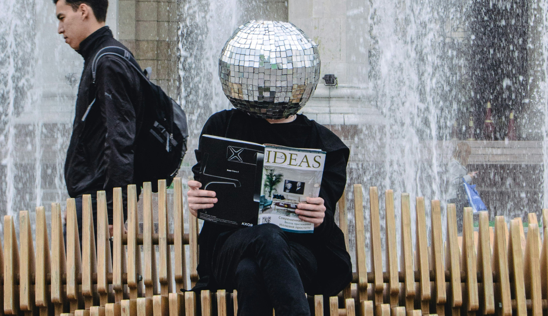 man with glitter ball head reading ideas magazine