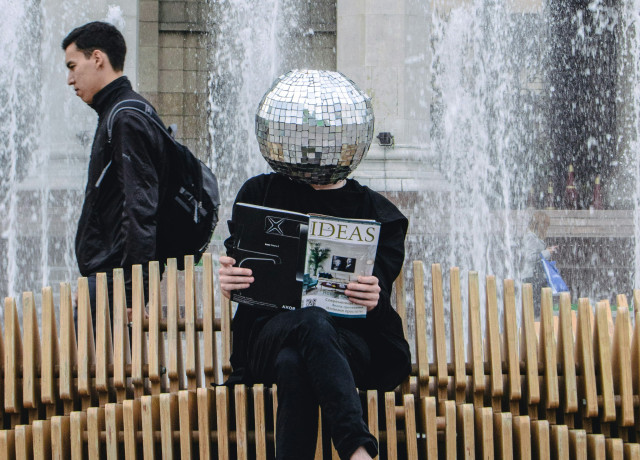 man with glitter ball head reading ideas magazine