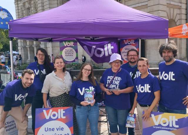 Huit personnes en teeshirt violet volt sous un parasol violet