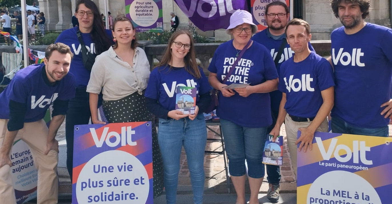 Huit personnes en teeshirt violet volt sous un parasol violet