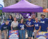 Huit personnes en teeshirt violet volt sous un parasol violet