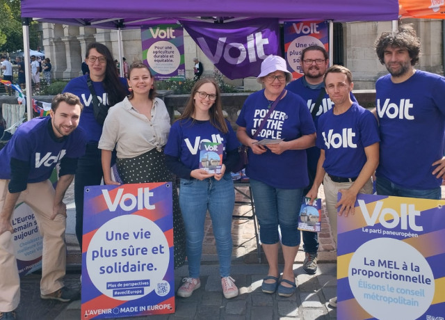 Huit personnes en teeshirt violet volt sous un parasol violet