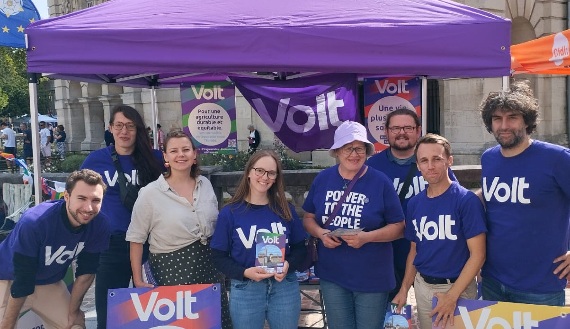 Huit personnes en teeshirt violet volt sous un parasol violet