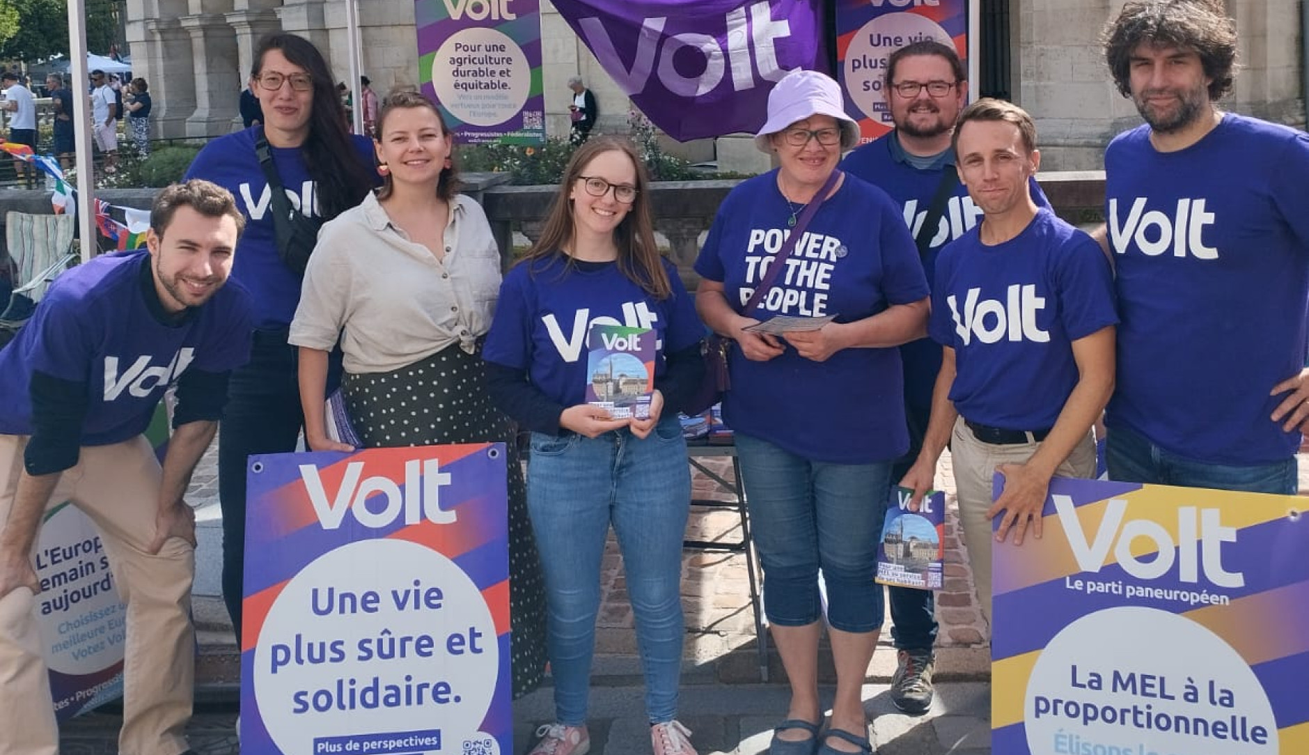 Huit personnes en teeshirt violet volt sous un parasol violet
