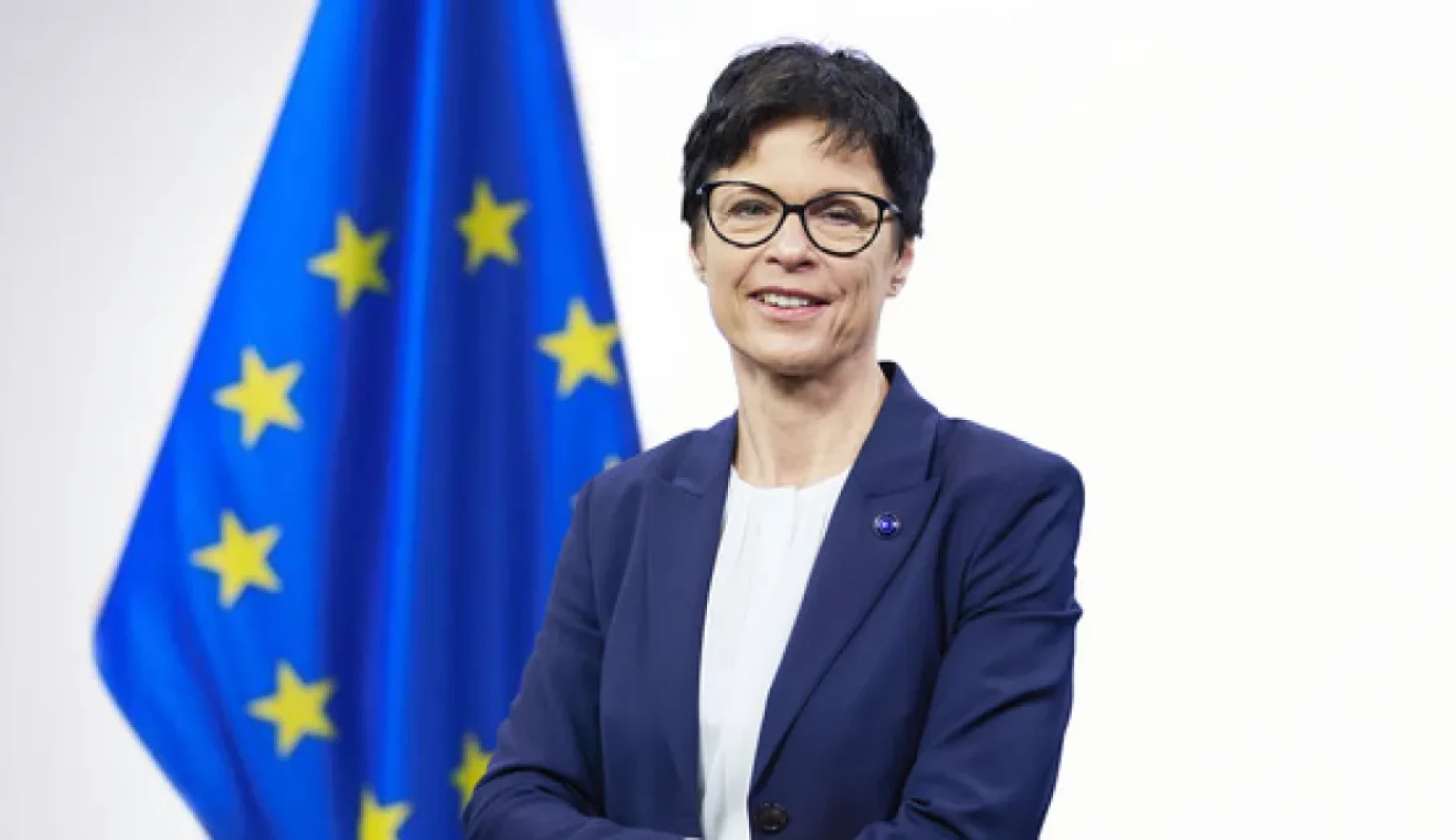 commissaire Kos devant drapeau européen