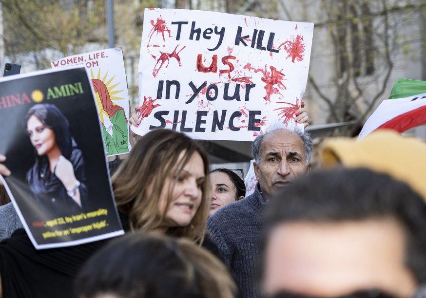 Manifestants en Iran avec une pancarte sur laquelle on peut lire « Ils nous tuent dans votre silence »