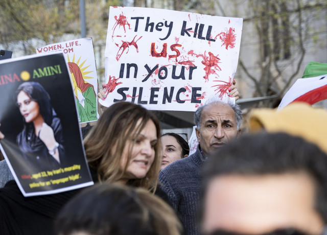 Manifestants en Iran avec une pancarte sur laquelle on peut lire « Ils nous tuent dans votre silence »