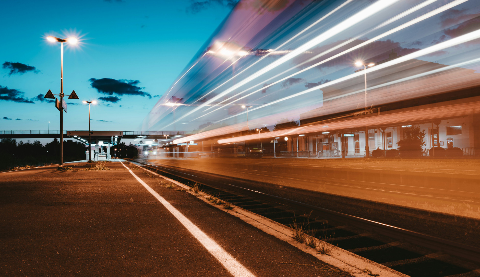 Train filant à toute vitesse dans une gare au coucher du soleil