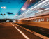 Train filant à toute vitesse dans une gare au coucher du soleil
