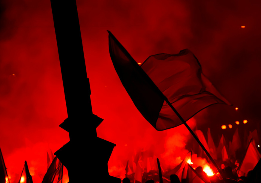 Drapeau flottant devant un monument avec des torches rouges allumées