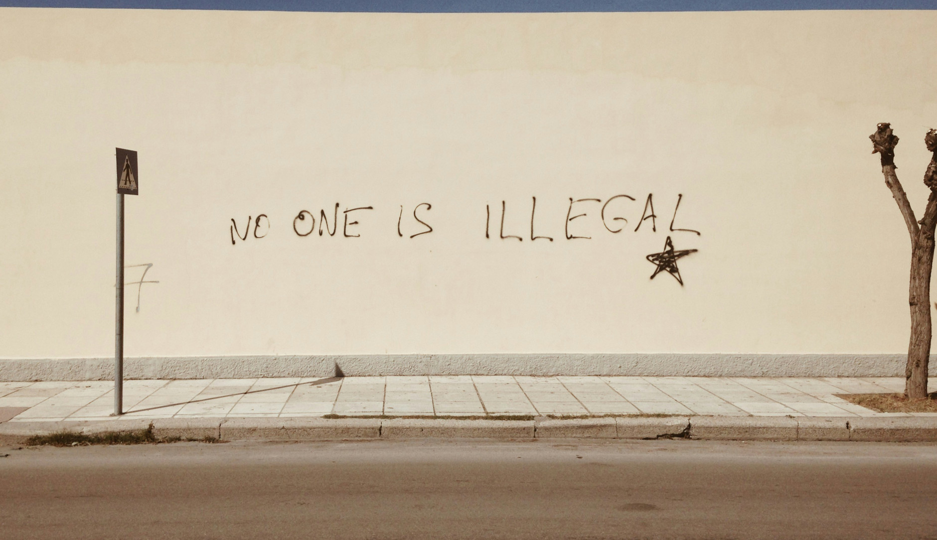 Un mur avec un graffiti disant « personne n'est illégal ».