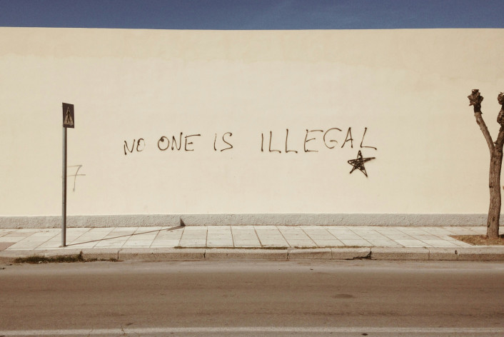 Un mur avec un graffiti disant « personne n'est illégal ».