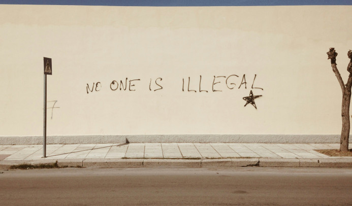 Un mur avec un graffiti disant « personne n'est illégal ».
