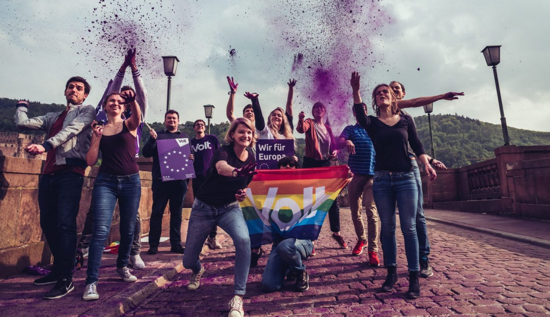 Des militants de Volt brandissant des drapeaux et de la farine violette