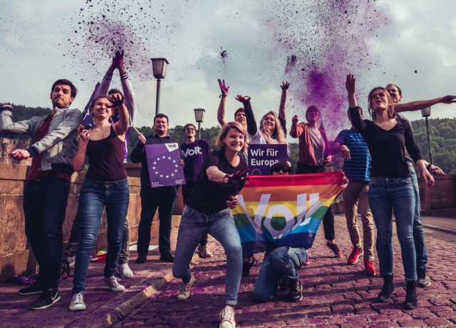 Des militants de Volt brandissant des drapeaux et de la farine violette