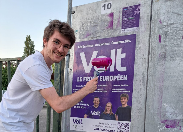 Le candidat Volt Felix Kleimann colle une affiche Volt