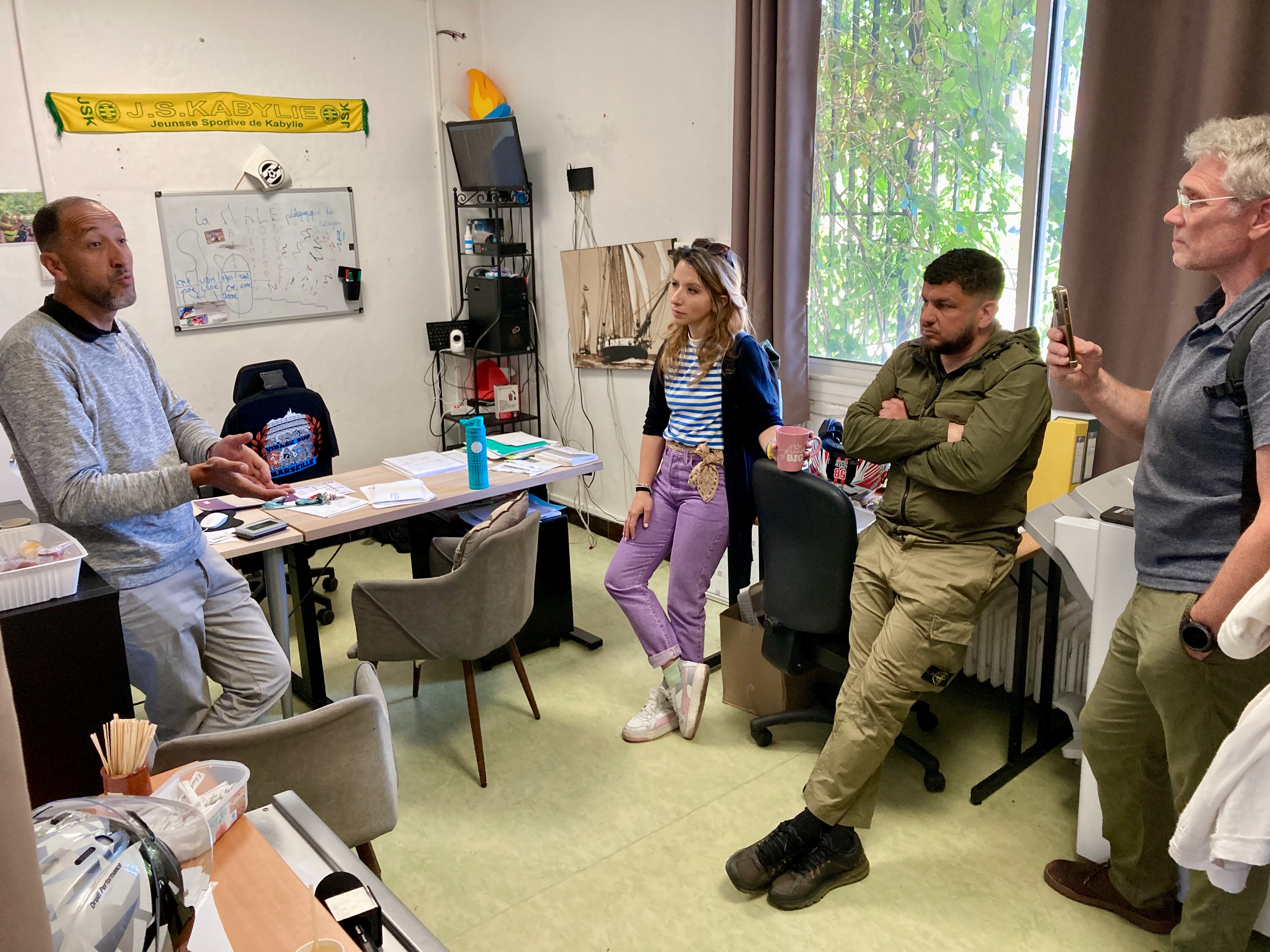 1 femme et 3 hommes debout dans un bureau