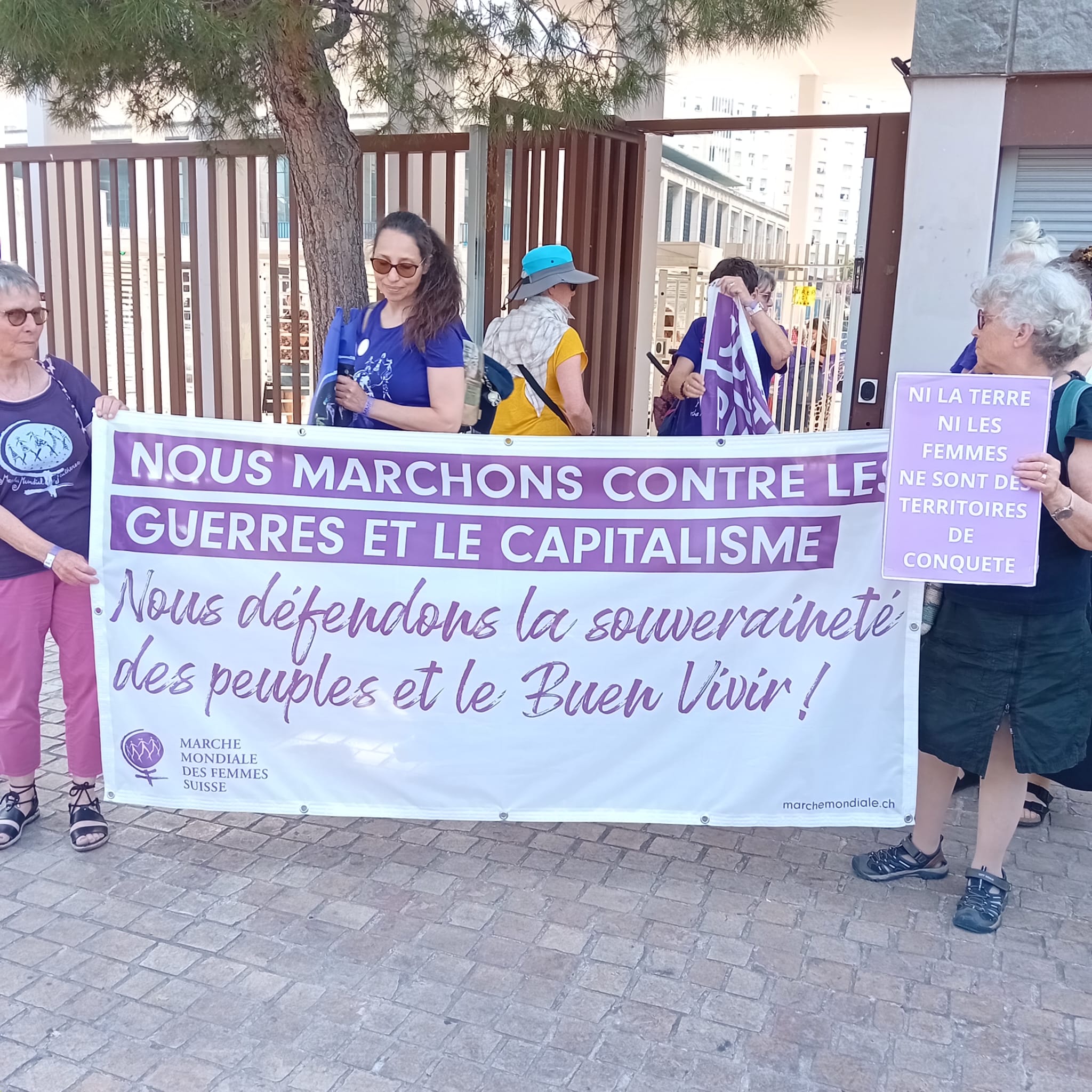 une banderolle tenue par des femmes  disant nous marchons contre les guerres et le capitalisme et nous defendon la souveraineté des peuple et le buen vivir un pancarte dit ni la terre ni les femmes ne sont des territoires de conquêtes
